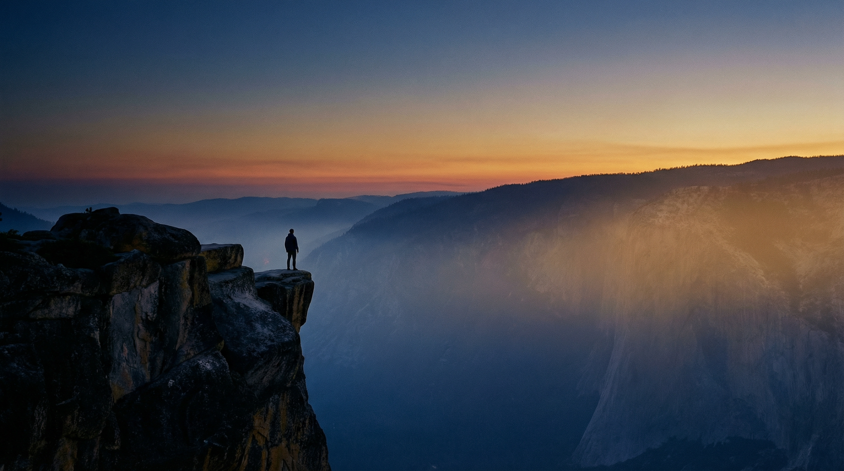 Silhouette of an explorer standing at cliff edge at dusk